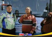 Satlantas Polres Gresik mendampingi pasangan suami istri pemudik asal Situbondo di depan bus mudik gratis.