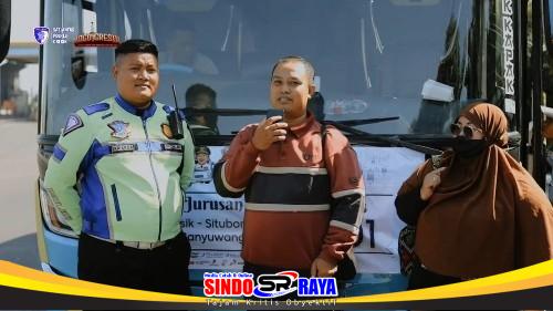 Satlantas Polres Gresik mendampingi pasangan suami istri pemudik asal Situbondo di depan bus mudik gratis.