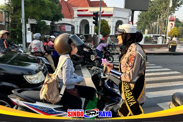 Polwan Satlantas Polrestabes Surabaya memberikan cokelat kepada pengendara perempuan saat peringatan Hari Kartini 2026 di simpang Polisi Istimewa
